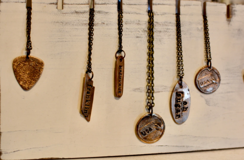 A display of various metal necklaces with unique pendants hanging on a wooden board.