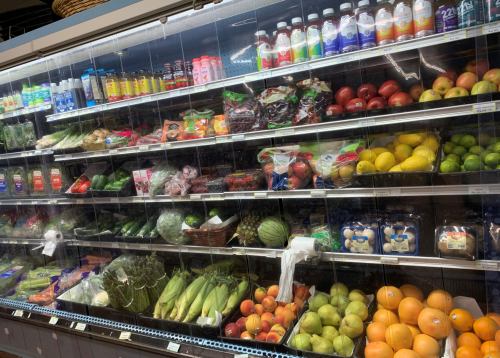 A grocery store display featuring a variety of fruits, vegetables, and beverages on shelves.