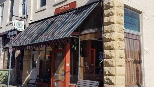 A storefront with a striped awning, large windows, and a welcoming entrance, located on a city street.