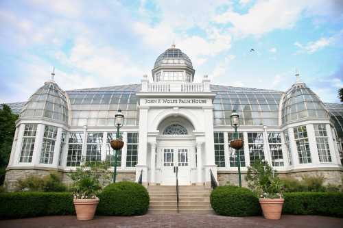 A large glass conservatory with a dome, surrounded by greenery and steps leading to the entrance.