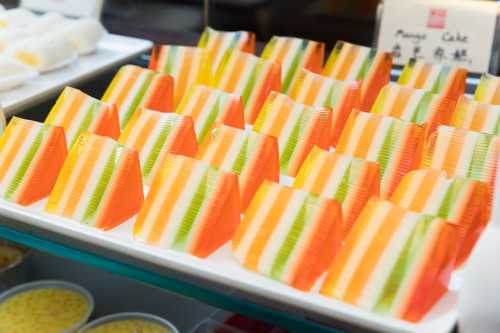 Colorful layered jelly desserts in orange, green, and yellow arranged neatly on a white platter.