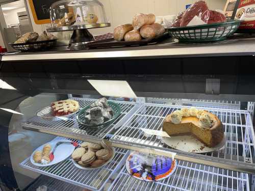 A display case filled with various baked goods, including cakes, cookies, and rolls, on a countertop.