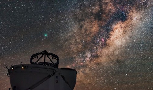 A telescope silhouette against a starry sky filled with the Milky Way and a visible comet.