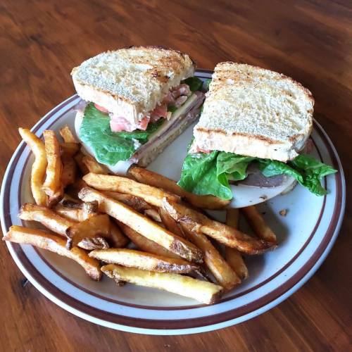 A plate with a toasted sandwich filled with lettuce and tomato, accompanied by a side of golden French fries.