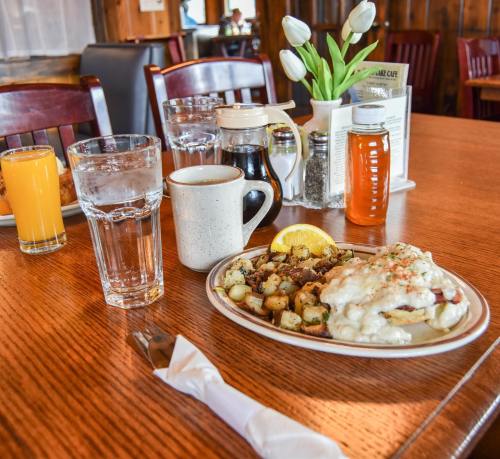 A breakfast table featuring a plate of hash browns and eggs, a glass of water, orange juice, and a coffee mug.