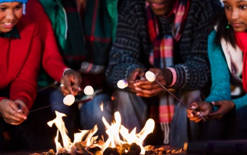 A group of people roasting marshmallows over a campfire, enjoying a cozy outdoor gathering.