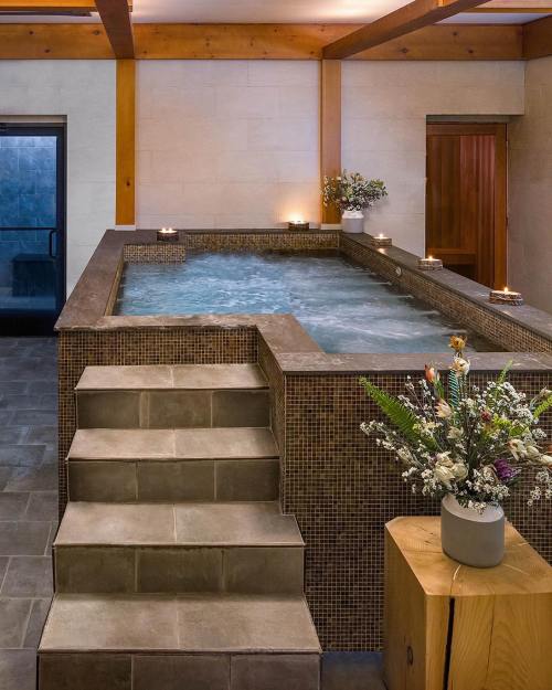 A serene spa area featuring a hot tub, steps, and decorative flowers in a tranquil setting.