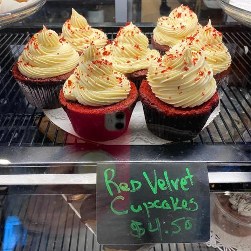 A display of red velvet cupcakes with cream cheese frosting, topped with red sprinkles, priced at $4.50.