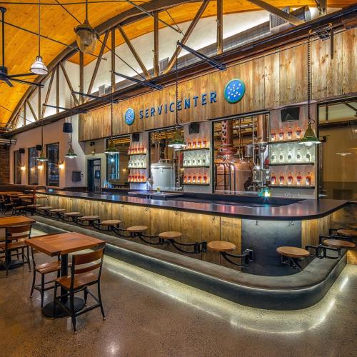 A modern bar with wooden accents, illuminated shelves, and a sleek counter in a spacious, stylish interior.