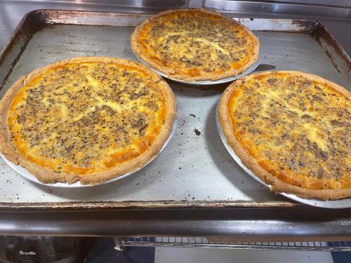 Three freshly baked savory pies with golden crusts and a meaty filling on a baking tray.