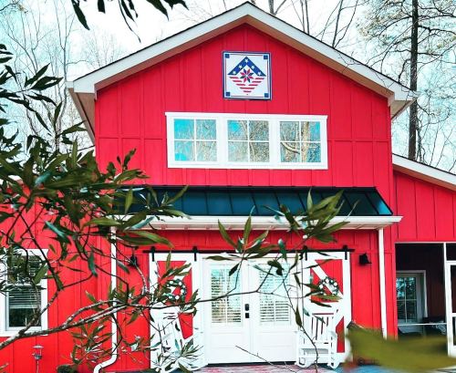 A bright red building with a decorative emblem on the front, surrounded by greenery and trees.