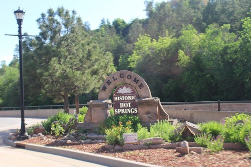 Welcome sign for Historic Hot Springs, surrounded by greenery and landscaping.