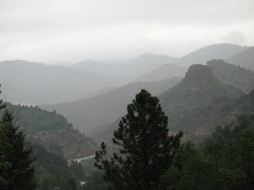 Foggy mountains with lush greenery and a winding road, creating a serene and misty landscape.