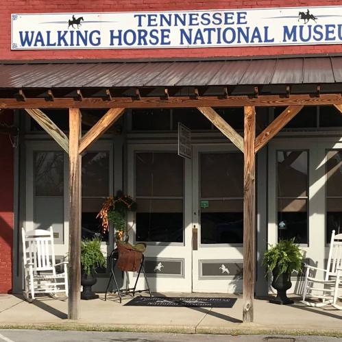 Entrance of the Tennessee Walking Horse National Museum, featuring rocking chairs and potted plants.