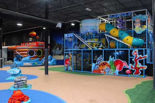 Colorful indoor playground featuring slides, climbing structures, and ocean-themed decorations.