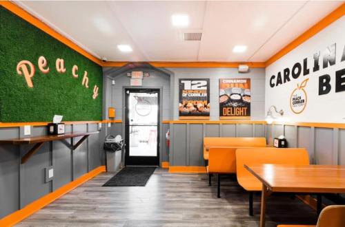 Interior of a cozy restaurant with orange accents, green wall decor, and wooden tables. Bright and inviting atmosphere.