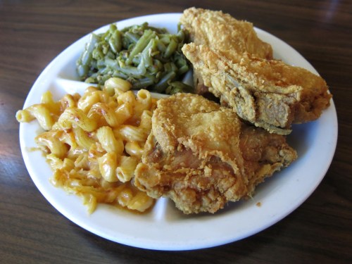 A plate of fried chicken, macaroni and cheese, and green beans served in a divided dish.