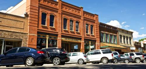 Historic brick buildings line a street with parked cars under a clear blue sky.