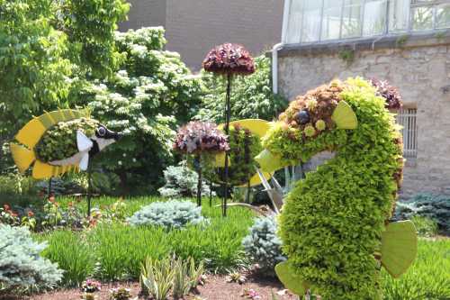 Colorful topiary sculptures of a seahorse and fish surrounded by lush greenery in a garden setting.