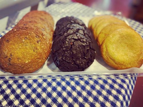 A tray of assorted cookies: chocolate chip, dark chocolate, and golden cookies, arranged on a blue checkered cloth.