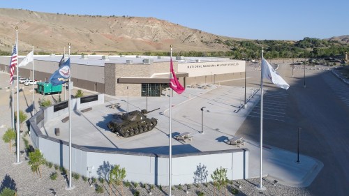 Aerial view of the National Museum of Military Vehicles, featuring flags and a tank in front of the building.