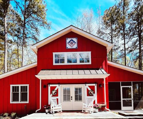 A red house with a white porch, surrounded by trees, featuring a decorative emblem on the front.
