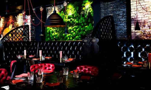 Chic restaurant interior with black leather booths, vibrant green wall decor, and stylish lighting.
