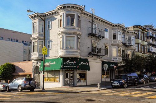 A corner building with a restaurant named "Mama's" on the ground floor, featuring a classic architectural style.