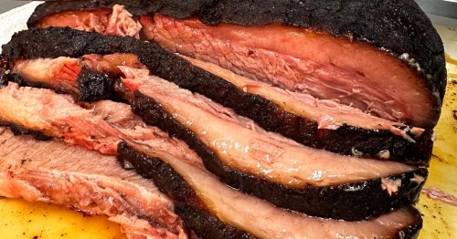 Sliced brisket with a smoky crust, showcasing tender, juicy meat and a rich, dark exterior.