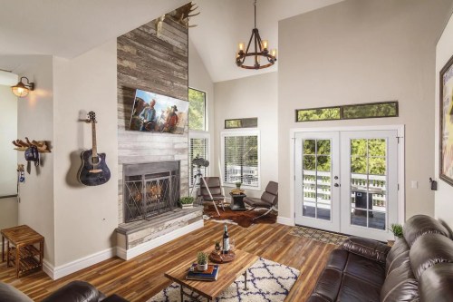 Cozy living room with a fireplace, guitar, large windows, and modern decor, featuring a TV and comfortable seating.