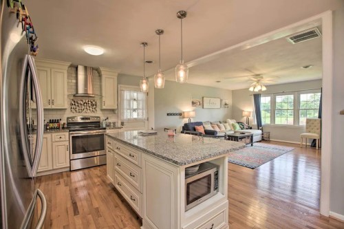 Bright kitchen with granite island, stainless steel appliances, and an open living area featuring a cozy seating arrangement.
