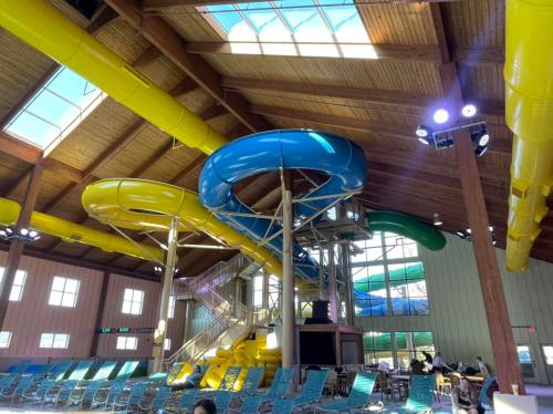 Indoor water park featuring colorful water slides, a spacious seating area, and large windows for natural light.