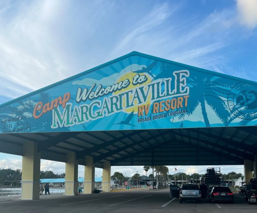 A colorful entrance sign for Camp Margaritaville RV Resort in Breaux Bridge, Louisiana, under a large canopy.