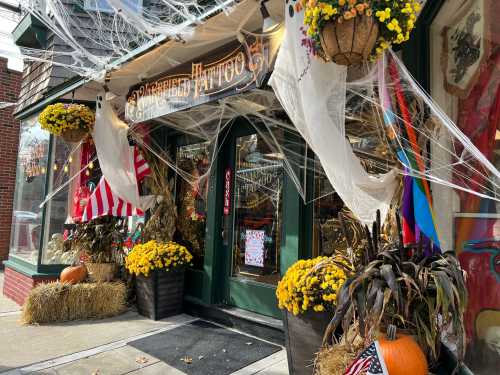 A tattoo shop decorated for Halloween with spider webs, pumpkins, and colorful flowers.