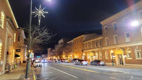 A charming street at night, lined with historic buildings and festive lights, creating a warm, inviting atmosphere.