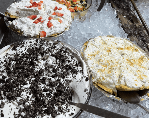 Three pies on ice: one with whipped cream and strawberries, one with crushed cookies, and a third with a creamy topping.