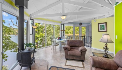 Cozy living space with large windows, a dining table, and a comfortable chair, overlooking a scenic view.