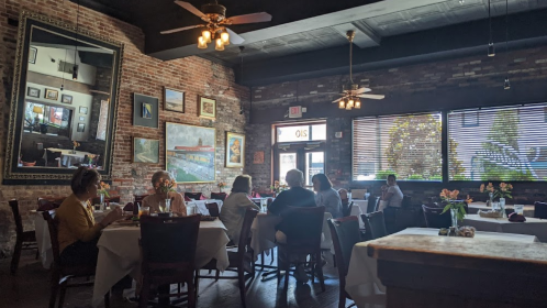 Cozy restaurant interior with brick walls, tables set for dining, and patrons enjoying their meals under warm lighting.