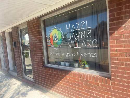 Window display of Hazel Jayne Village, featuring the logo and text "Gatherings & Events" on a brick building.