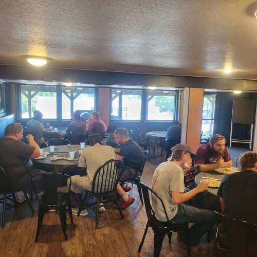 A casual dining area with people sitting at tables, enjoying meals and chatting in a well-lit space.