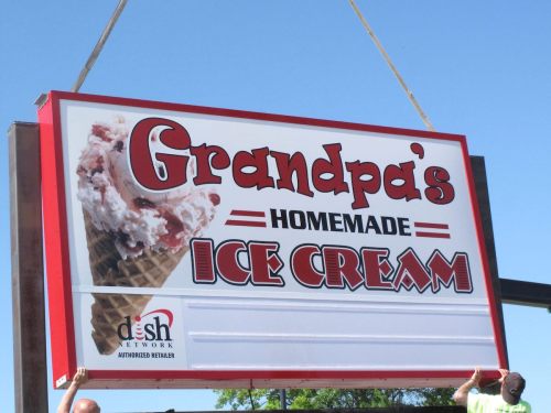 Sign for "Grandpa's Homemade Ice Cream" featuring an ice cream cone, with a clear blue sky in the background.