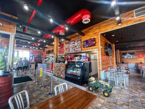 Interior of a casual restaurant with wooden decor, a counter, menu boards, and customers dining.