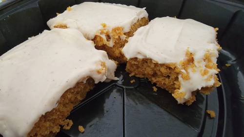 Three pieces of frosted cake with a crumbly texture, displayed in a black container.