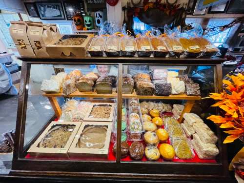 A display case filled with various baked goods, including cookies, bars, and treats, with festive decorations in the background.