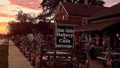 A cozy bakery and café sign at sunset, surrounded by autumn decorations and a peaceful street scene.