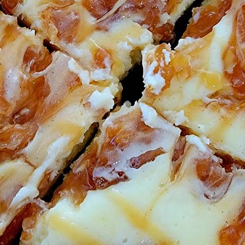 Close-up of creamy dessert squares with a swirled caramel topping and a golden crust.