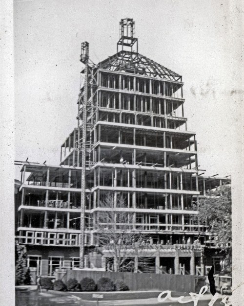 Black and white photo of a partially constructed building with a steel frame and scaffolding.