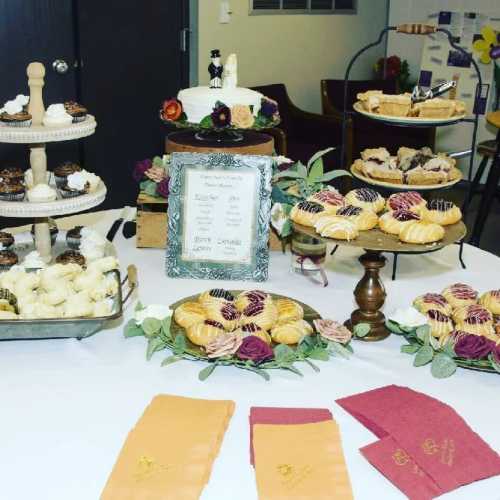 A beautifully arranged dessert table featuring various pastries, cupcakes, and decorative flowers.