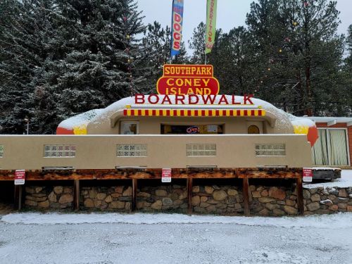 A colorful retro diner with a snow-covered exterior, surrounded by trees and festive decorations.