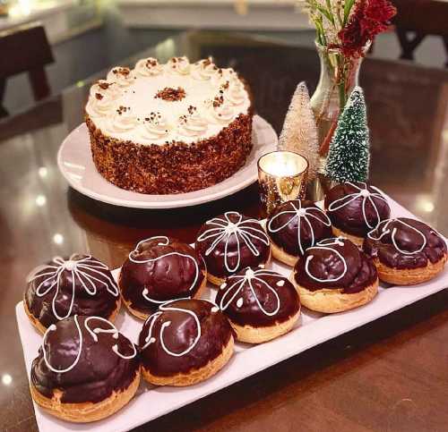 A festive dessert display featuring a cake and chocolate-covered pastries with white icing decorations.